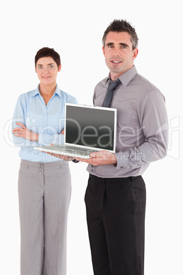 Portrait of a man showing a laptop while his colleague is posing