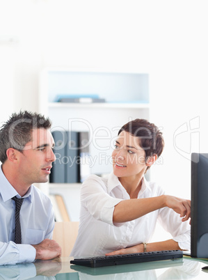 Woman pointing at something to her colleague on a screen