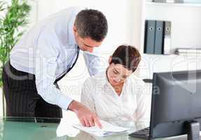 Business manager showing something on a document to his secretar
