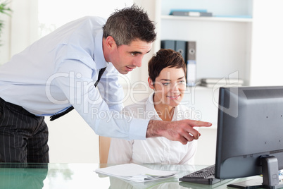 Businessman pointing at something on a screen to his secretary