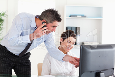 Businessman pointing at something on a screen to his colleague