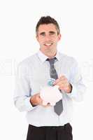 Man putting a bank note in a piggy bank