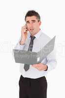 Portrait of a man making a phone call while holding a binder