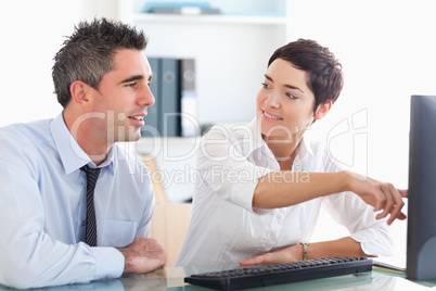 Office worker pointing a something on a screen to her colleague