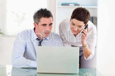 Coworkers working with a laptop and a cellphone