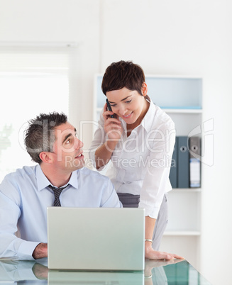 Portrait of a woman making a phone call while her colleague is w