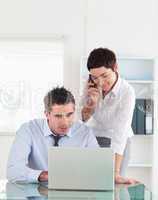 Portrait of a woman making a phone call while her colleague is l