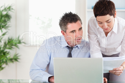 Office workers comparing a blueprint document to an electronic o