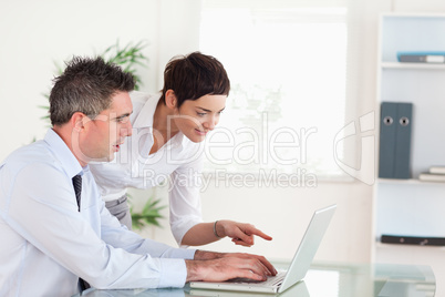 Woman pointing at something to her colleague on a laptop