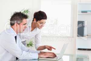 Woman pointing at something to her colleague on a laptop
