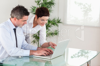 Businesswoman pointing at something to her colleague on a laptop