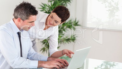 Businesswoman pointing at something to her colleague on a notebo
