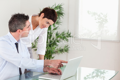 Man pointing at something to his colleague on a laptop