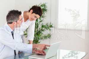 Man pointing at something to his colleague on a laptop