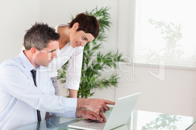 Businessman pointing at something to his colleague on a laptop