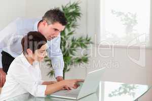 Woman pointing at something to his colleague on a notebook