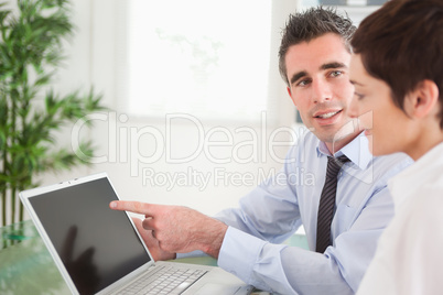 Manager pointing at something to his secretary on a laptop