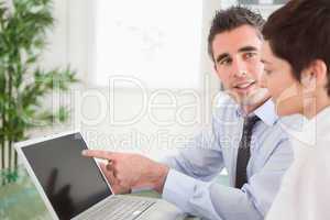 Manager pointing at something to his secretary on a laptop