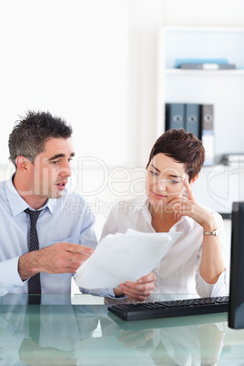 Manager pointing at something to his secretary on a blueprint do
