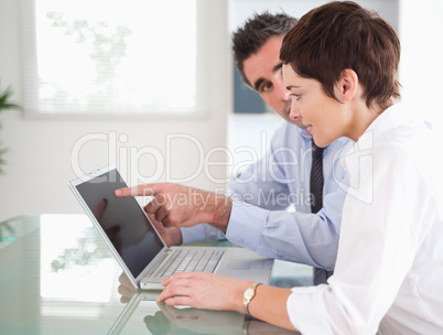 Man pointing at something to his secretary on a laptop