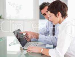 Man pointing at something to his secretary on a laptop