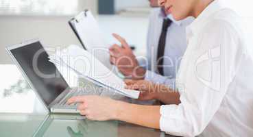 Office workers typing a report from blueprint documents