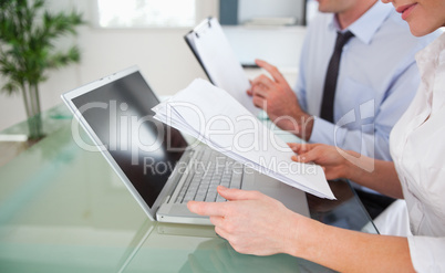 Managers typing a report from blueprint documents