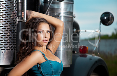 Young pretty girl in jeans stand near steel truck