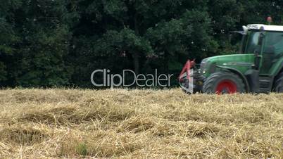 a tractor machine is harvesting hay from wheat
