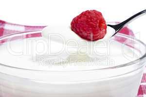 himbeere auf einem löffel mit joghurt über einem dessert auf einem tuch