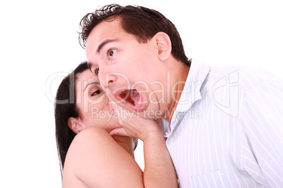 Woman tells something into surprised guy's ear isolated on white