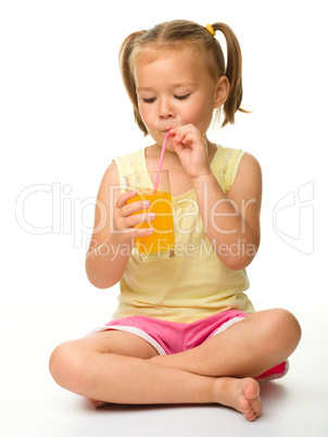 Little girl drinks orange juice