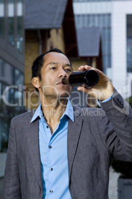 Smart casual business man drinking beer outdoors portrait in front of modern office building