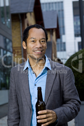 Smart casual business man drinking beer outdoors portrait in front of modern office building