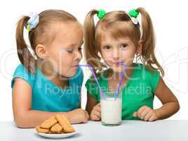 Two little girls are drinking milk