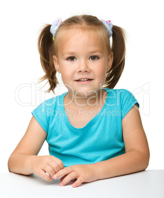 Happy little girl is sitting at the table