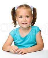 Happy little girl is sitting at the table