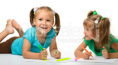 Two little girls draw with markers