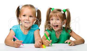 Two little girls draw with markers