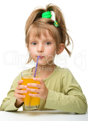 Cute little girl is drinking orange juice