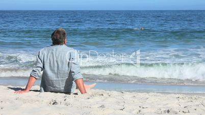 Mann sitzt am Strand