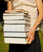 Teen girl holds a stack of books