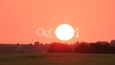 Sunset on red sky over cultivated field time-lapse