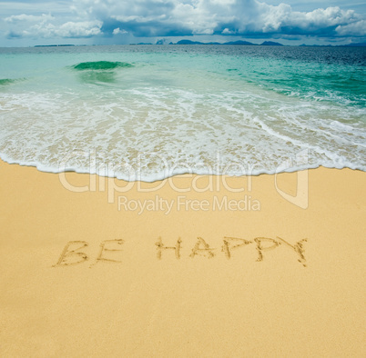 be happy written in a sandy tropical beach
