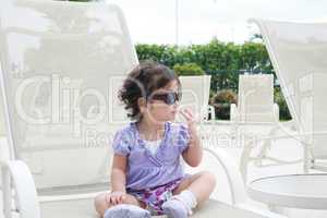 adorable young baby girl wearing sunglasses in flirting position