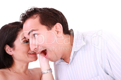 girl tells something into surprised guy's ear isolated on white