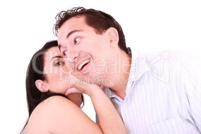 pretty girl talking secret to young man in his ear, man smiling