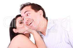 pretty girl talking secret to young man in his ear, man smiling