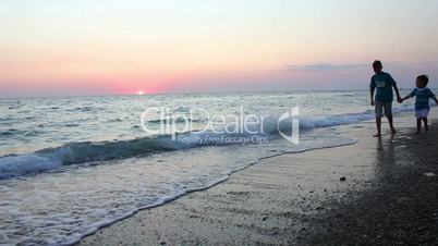 Children walking on the beach at sunset