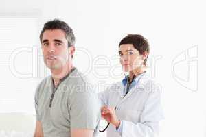 Charming Doctor examining a patient with a stethoscope